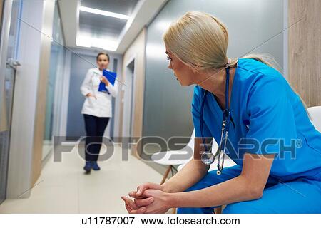 Surgeon sitting in hospital hallway, leaning forward, doctor walking along hallway View Large Photo Image Stock Photo - Surgeon sitting in hospital hallway, leaning forward, doctor walking along hallway. Fotosearch
