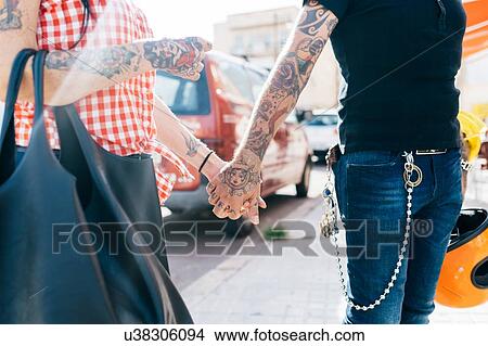Tattooed hipster couple holding hands on sidewalk, mid section View Large Photo Image Picture - Tattooed hipster couple holding hands on sidewalk, mid section. Fotosearch