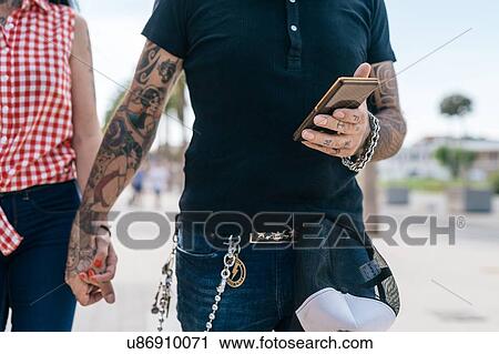 Tattooed hipster couple holding hands and smartphone, mid section View Large Photo Image Stock Image - Tattooed hipster couple holding hands and smartphone, mid section. Fotosearch