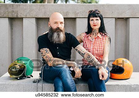 Tattooed hipster couple sitting on wall, portrait View Large Photo Image Stock Image - Tattooed hipster couple sitting on wall, portrait. Fotosearch