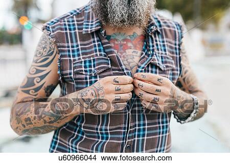 Picture - Tattooed male hipster fastening shirt buttons, cropped. Fotosearch