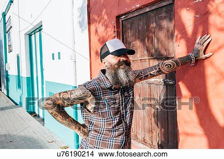 Tattooed male hipster leaning against sunlit wall View Large Photo Image Picture - Tattooed male hipster leaning against sunlit wall. Fotosearch