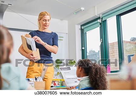 Teacher handing out papers in classroom at primary school View Large Photo Image Stock Photography - Teacher handing out papers in classroom at primary school. Fotosearch