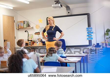 Picture - Teacher with hands on hips in front of class at primary school. Fotosearch