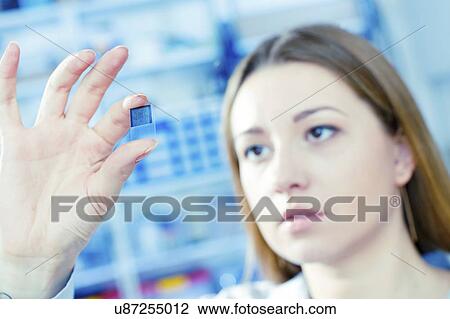 Stock Image - Technician examining microchip in microelectronics laboratory.. Fotosearch