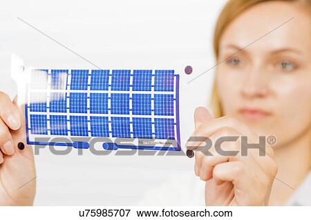 Stock Photo - Technician holding a solar cell printed on flexible film.. Fotosearch