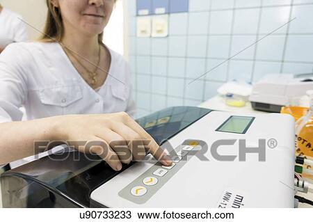 Stock Image - Technician using a PCR (polymerase chain reaction) machine to amplify segments of DNA (deoxyribonucleic acid).. Fotosearch