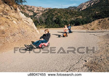 Stock Photography - Three children, rolling downhill of toy cars. Fotosearch