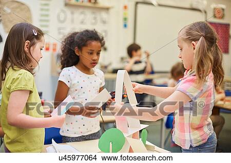 Three primary schoolgirls making paper pyramid in classroom View Large Photo Image Picture - Three primary schoolgirls making paper pyramid in classroom. Fotosearch