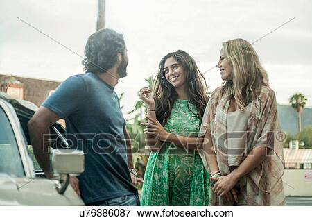 Three young adults, standing beside car, talking View Large Photo Image Stock Photo - Three young adults, standing beside car, talking. Fotosearch