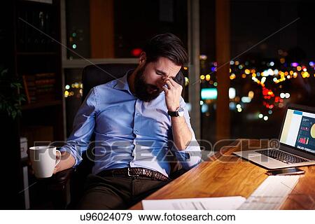 Tired young businessman at office desk at night View Large Photo Image Stock Photo - Tired young businessman at office desk at night. Fotosearch