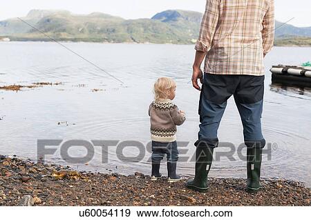Toddler and father at fjord water's edge looking out, Aure, More og Romsdal, Norway View Large Photo Image Stock Photo - Toddler and father at fjord water's edge looking out, Aure, More og Romsdal, Norway. Fotosearch