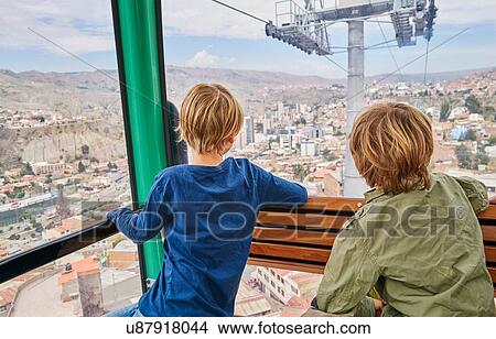 Picture - Two boys in cable car, looking our of window at view, rear view, La Paz, Bolivia, South America. Fotosearch