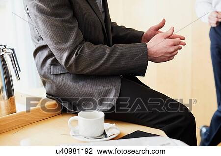 Stock Image - Two businessman chatting in office, cropped. Fotosearch