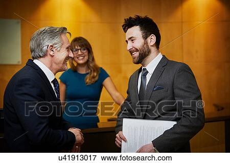 Stock Photo - Two businessmen meeting in reception. Fotosearch