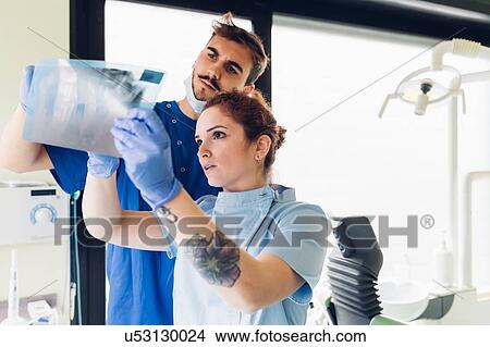 Picture - Two dentists in dentist office, looking at dental x-ray. Fotosearch