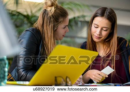 Stock Photo - Two female designers looking at colour swatches at design studio desk. Fotosearch