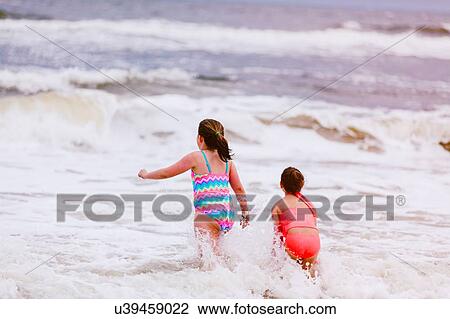 Two girls playing in ocean waves, rear view, Dauphin Island, Alabama, USA View Large Photo Image Stock Image - Two girls playing in ocean waves, rear view, Dauphin Island, Alabama, USA. Fotosearch