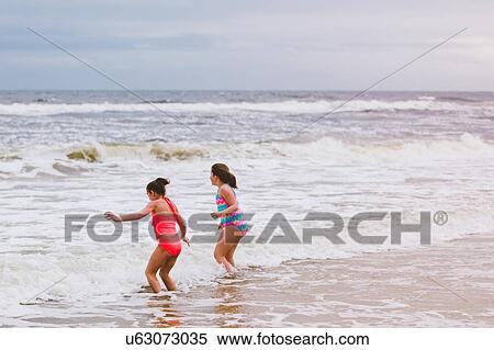 Two girls playing in ocean waves, Dauphin Island, Alabama, USA View Large Photo Image Stock Photography - Two girls playing in ocean waves, Dauphin Island, Alabama, USA. Fotosearch