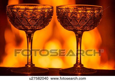 Two ornate champagne glasses on table in front of burning fire View Large Photo Image Stock Image - Two ornate champagne glasses on table in front of burning fire. Fotosearch
