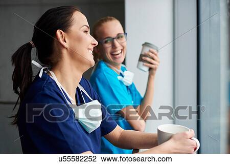 Two surgeons taking a break, looking out of window, holding coffee cups View Large Photo Image Stock Image - Two surgeons taking a break, looking out of window, holding coffee cups. Fotosearch