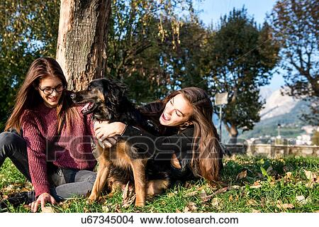Two young women hugging dog, Calolziocorte, Lombardy, Italy View Large Photo Image Picture - Two young women hugging dog, Calolziocorte, Lombardy, Italy. Fotosearch