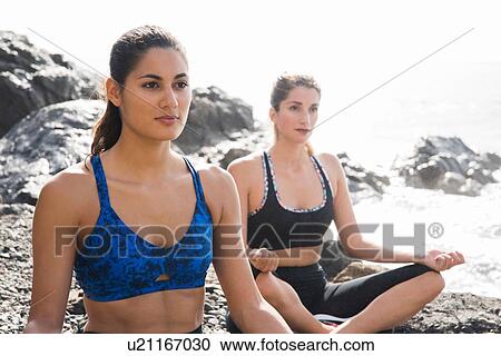 Stock Image - Two young women practicing yoga lotus pose on beach, Las Palmas, Canary Islands, Spain. Fotosearch