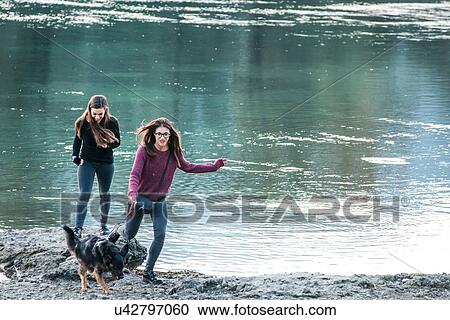 Two young women running with dog by river, Calolziocorte, Lombardy, Italy View Large Photo Image Stock Image - Two young women running with dog by river, Calolziocorte, Lombardy, Italy. Fotosearch