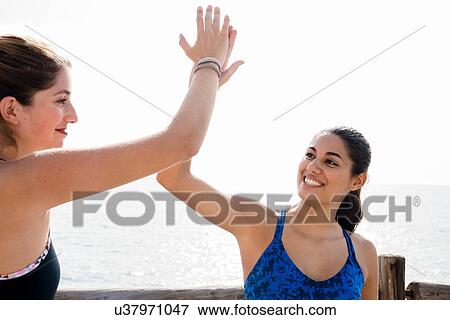 Two young women training together on sea waterfront, high fiving View Large Photo Image Stock Photo - Two young women training together on sea waterfront, high fiving. Fotosearch