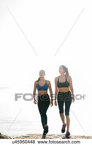 Two young women training, walking on beach View Large Photo Image Stock Photo - Two young women training, walking on beach. Fotosearch