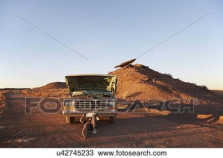 Stock Image - USA, Arizona, Man repairing broken pick-up truck. Fotosearch