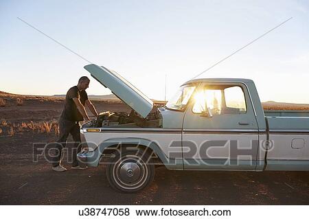 Stock Photo - USA, Arizona, Man repairing broken pick-up truck. Fotosearch