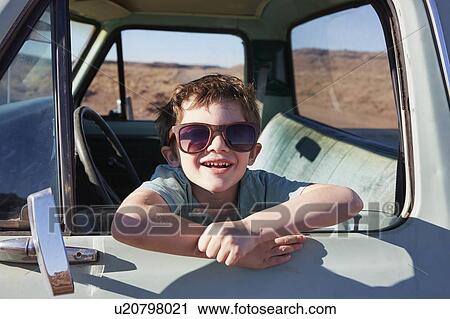 Stock Image - USA, Arizona, Portrait of smiling boy (6-7) sitting in pick-up truck. Fotosearch