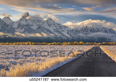 Stock Photo - USA, Wyoming, Country road and Teton Range at sunset. Fotosearch
