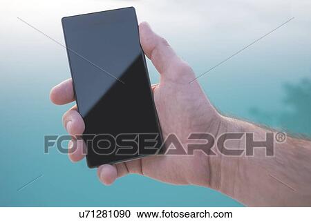 Stock Image - Using mobile phone by a swimming pool.. Fotosearch