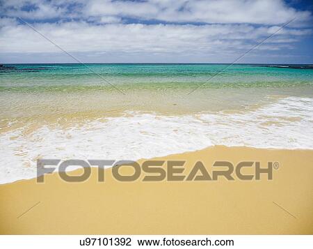 Stock Image - White clouds above sea and sandy beach. Fotosearch