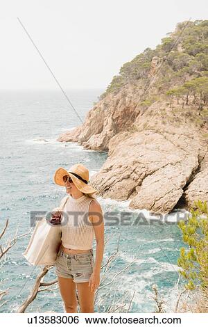 Stock Photograph - Woman along coastline, looking at view, Tossa de mar, Catalonia, Spain. Fotosearch