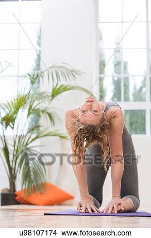 Picture - Woman at home, doing yoga, bending backwards, in yoga position. Fotosearch
