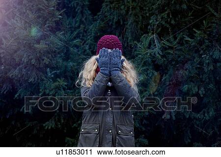 Woman covering face, fir tree in background View Large Photo Image Stock Image - Woman covering face, fir tree in background. Fotosearch