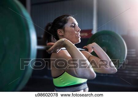 Woman exercising in gym, using barbell View Large Photo Image Stock Photo - Woman exercising in gym, using barbell. Fotosearch