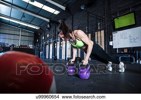 Picture - Woman exercising in gymnasium, using kettlebells. Fotosearch