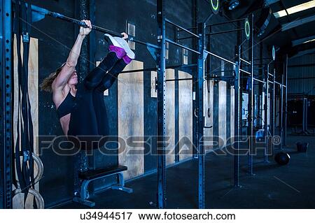 Stock Photo - Woman exercising in gymnasium, using pull up bars. Fotosearch