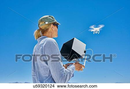 Picture - Woman flying drone, low angle view, Uyuni, Oruro, Bolivia, South America. Fotosearch