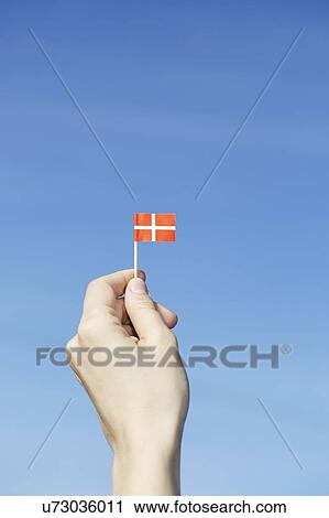 Stock Image - Woman holding Danish flag in hand. Fotosearch