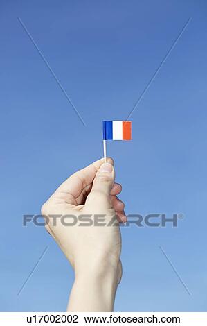Stock Image - Woman holding French flag in hand. Fotosearch