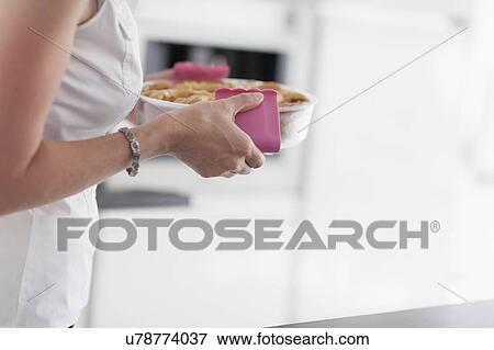 Stock Photo - Woman holding hot casserole dish. Fotosearch