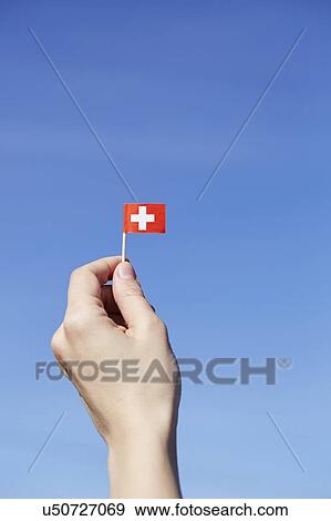 Stock Photo - Woman holding Swiss flag in hand. Fotosearch