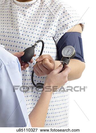 Stock Photo - Woman in hospital gown having blood pressure taken.. Fotosearch