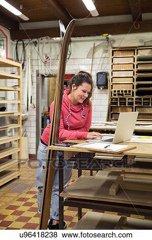Woman in workshop, using laptop, skis leaning against counter beside her View Large Photo Image Stock Photo - Woman in workshop, using laptop, skis leaning against counter beside her. Fotosearch