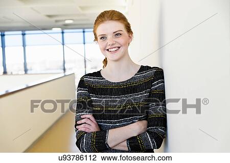 Stock Image - Woman leaning on wall with arms crossed. Fotosearch